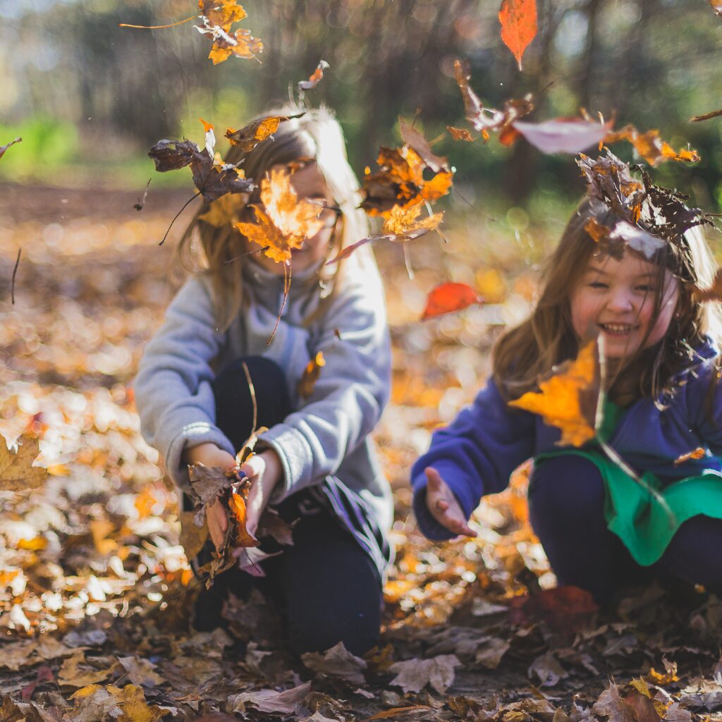 kids playing in autumn leaves at a nature camp